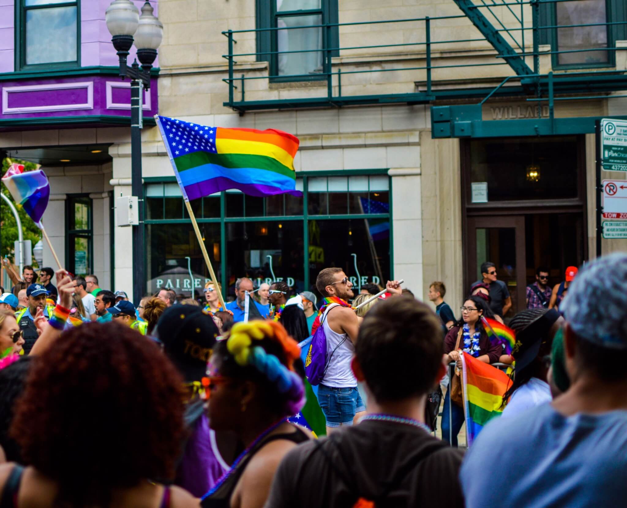 People waving a rainbow flag at ceremony.