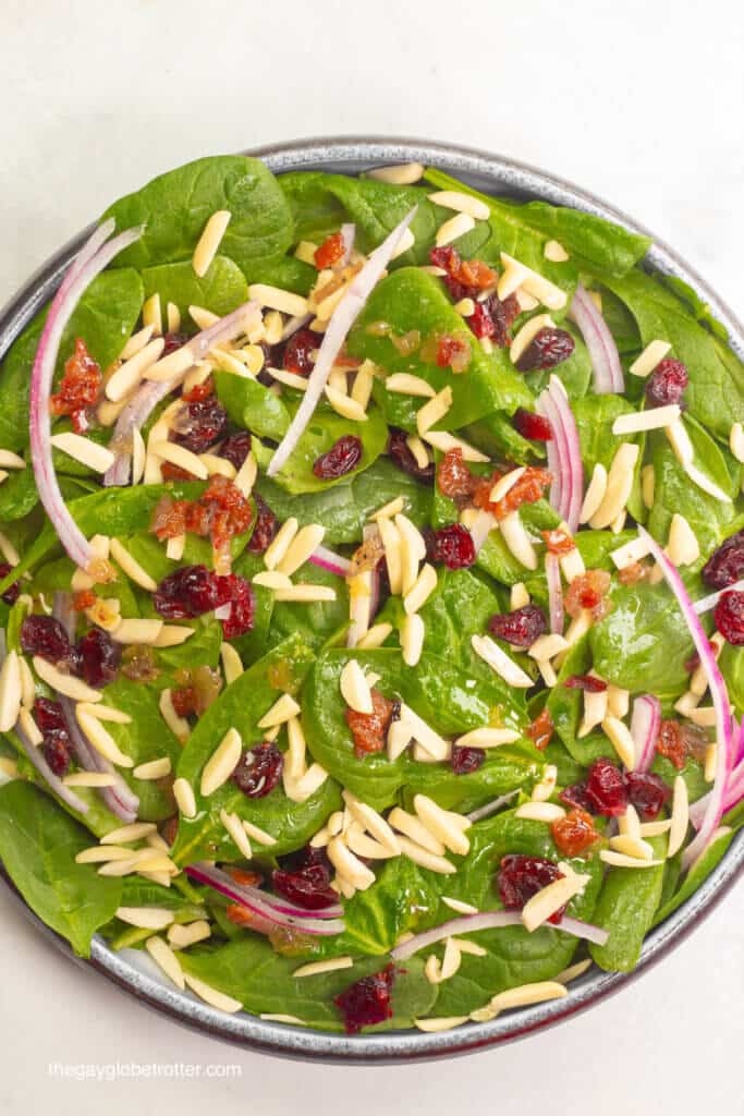 A bowl of spinach cranberry salad ready to be dressed.