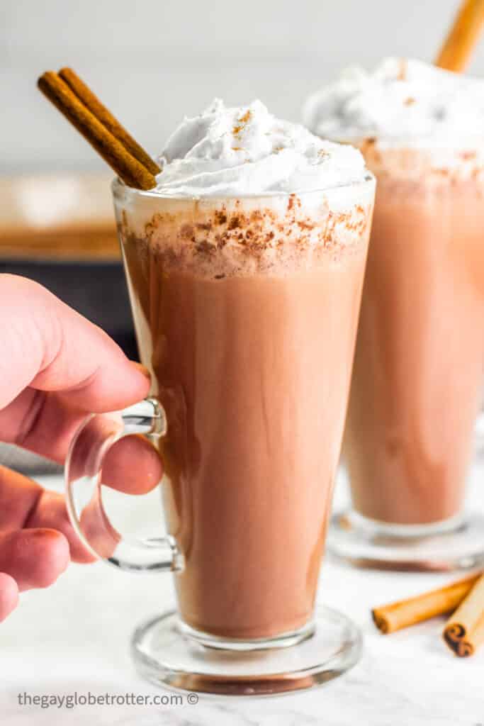 A hand holding a cup of Mexican hot chocolate.