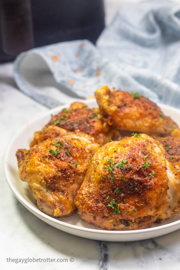 A plate of air fryer chicken thighs garnished with fresh parsley.