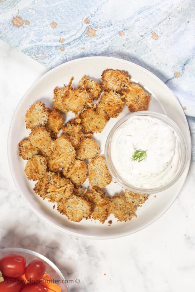 A plate of air fryer pickles with a bowl of dill dip.