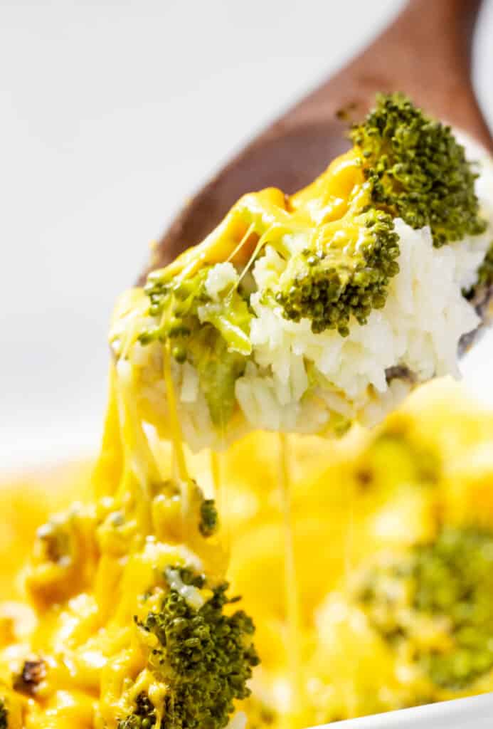 A spoon serving broccoli and rice with cheese.