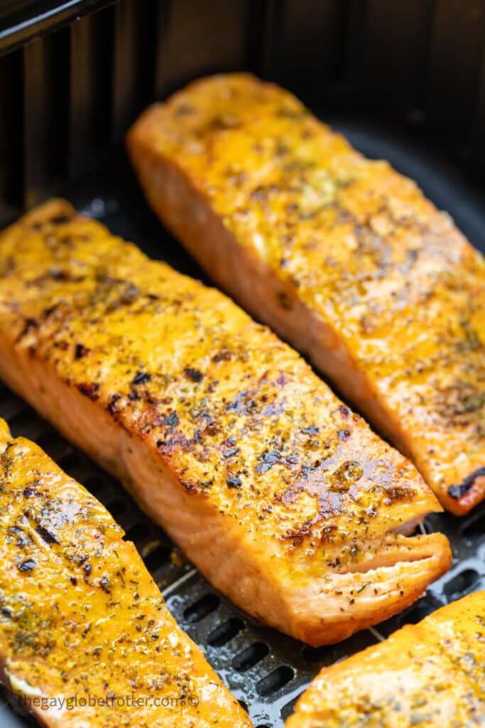 Cooked salmon in an air fryer basket.