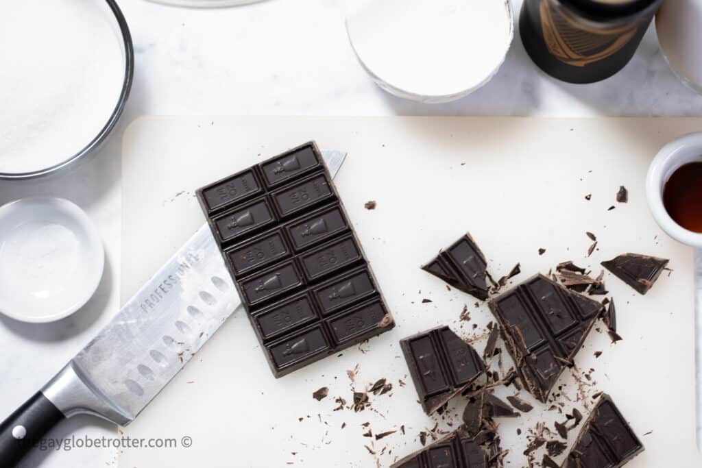 Dark chocolate being chopped on a cutting board.