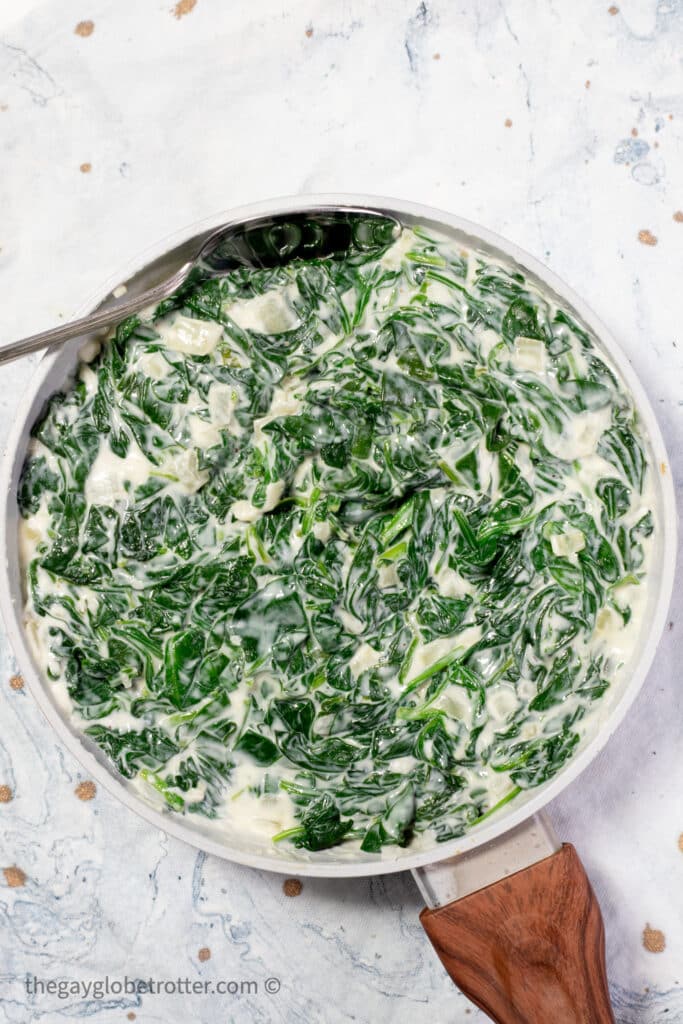 A pan of creamed spinach with a silver spoon.