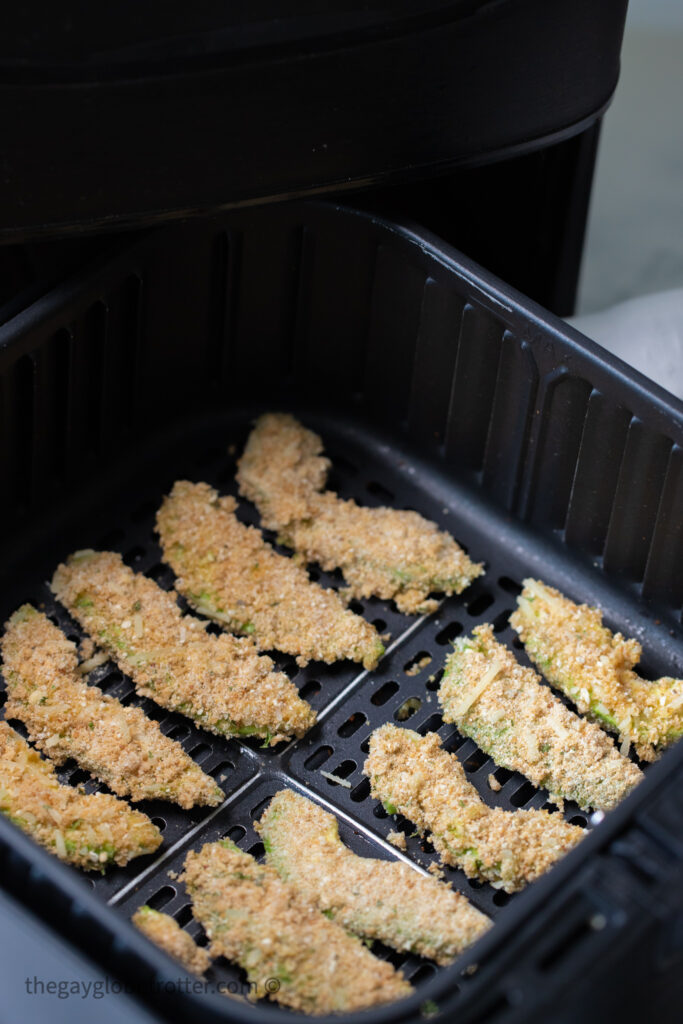 Uncooked avocado fries in an air fryer basket.