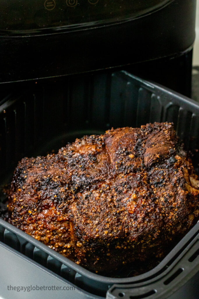 Roast beef in an air fryer basket.