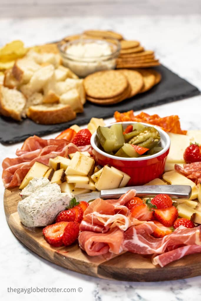 A charcuterie board next to crackers, crostini, and bread.