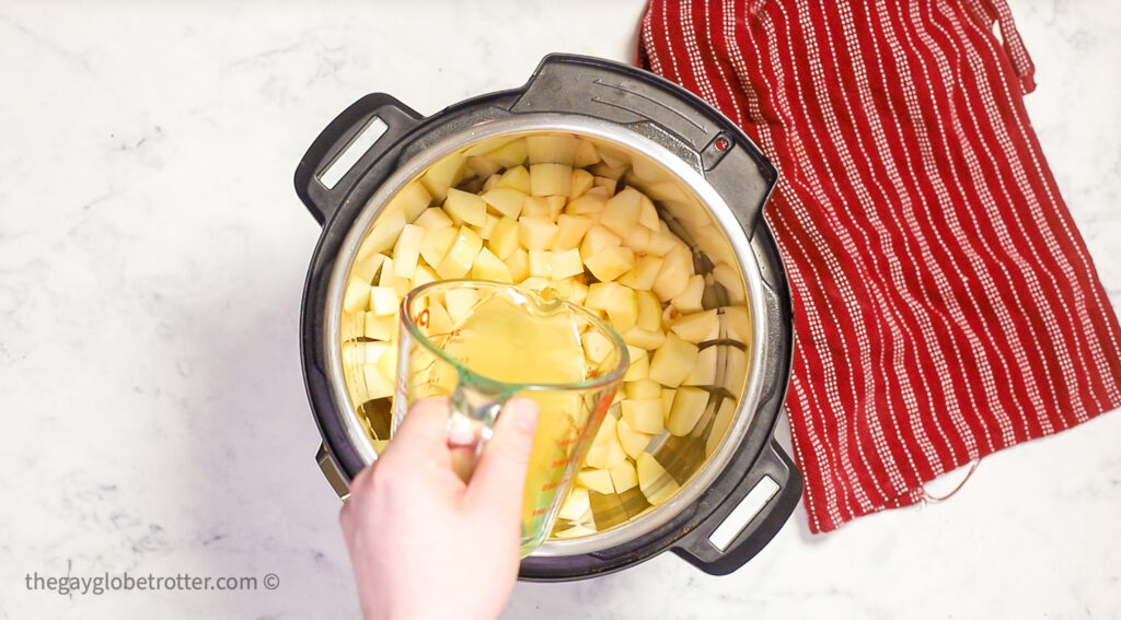 Chicken broth being poured over potato cubes.