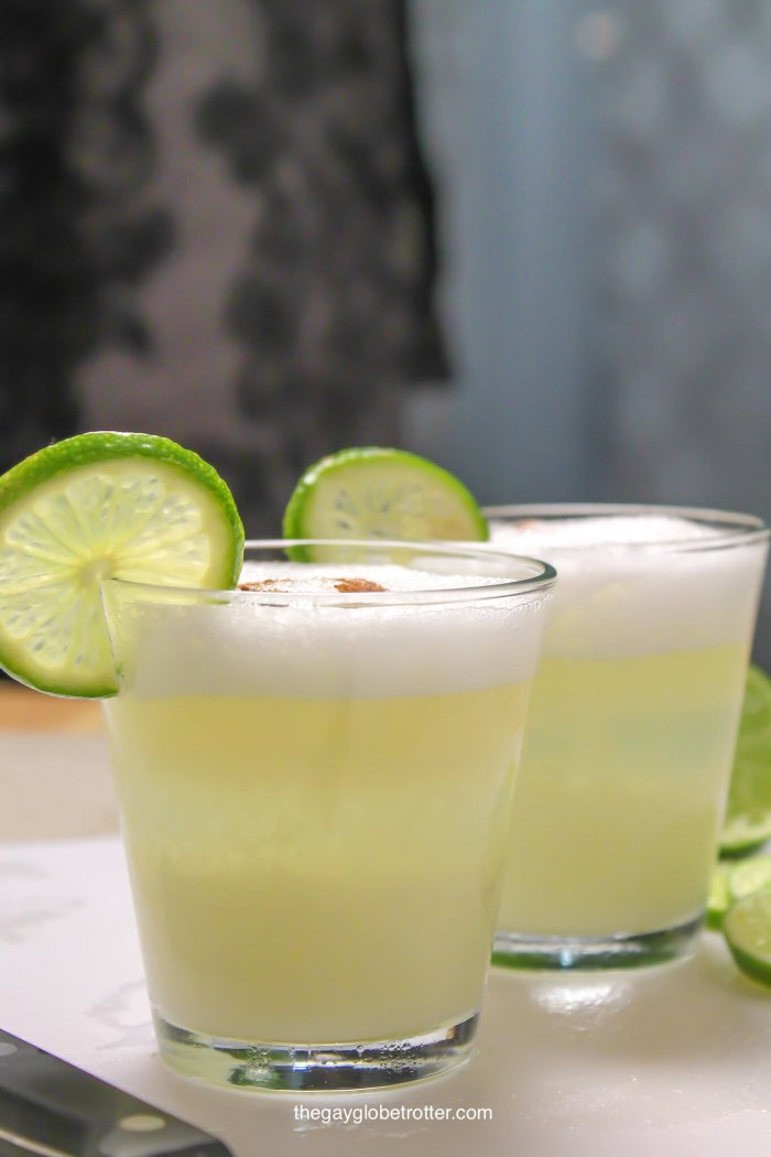 Peruvian pisco sours on a cutting board garnished with lime wedges.