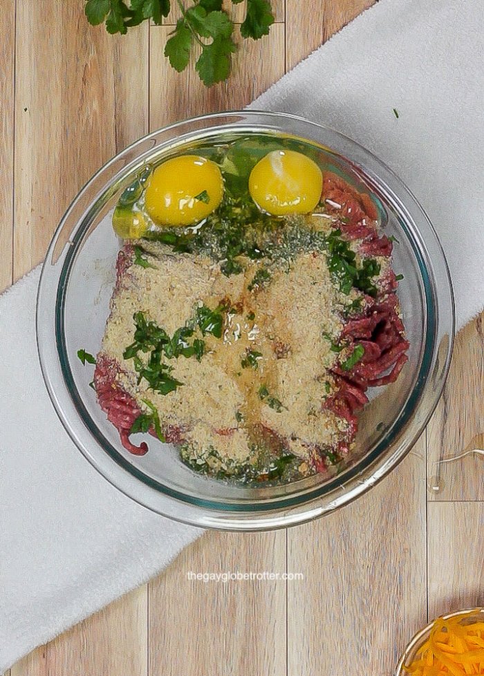 Ingredients for taco meatballs in a clear mixing bowl.